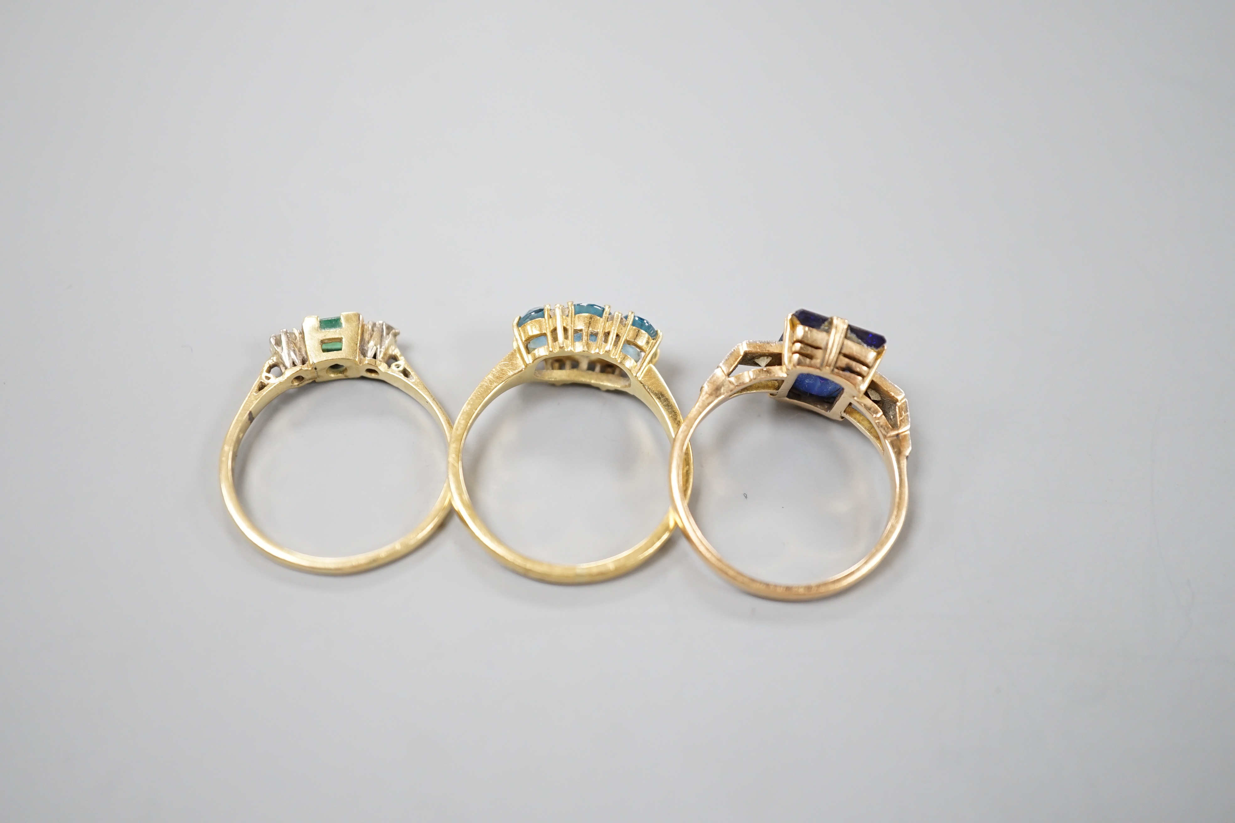 Three assorted 18ct and gem set dress rings, including emerald and diamond three stone, size Q/R, gross 11.7 grams.